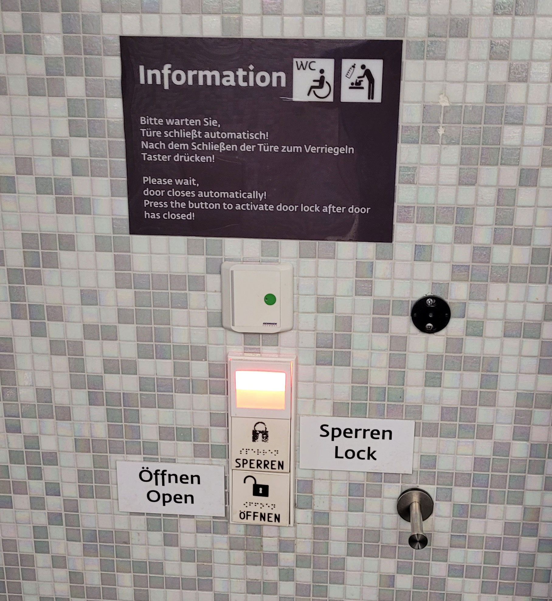 Panel sterujący na ścianie obok toalety z instrukcją w dwóch językach
