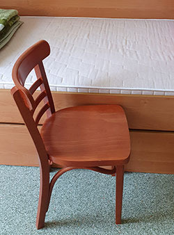 Na zdjęciu krzeszło przystawione do łóżka w celu ukazania wyskości łóżka. Łóżko jest wyższe niż krzeszło o pare centymetów