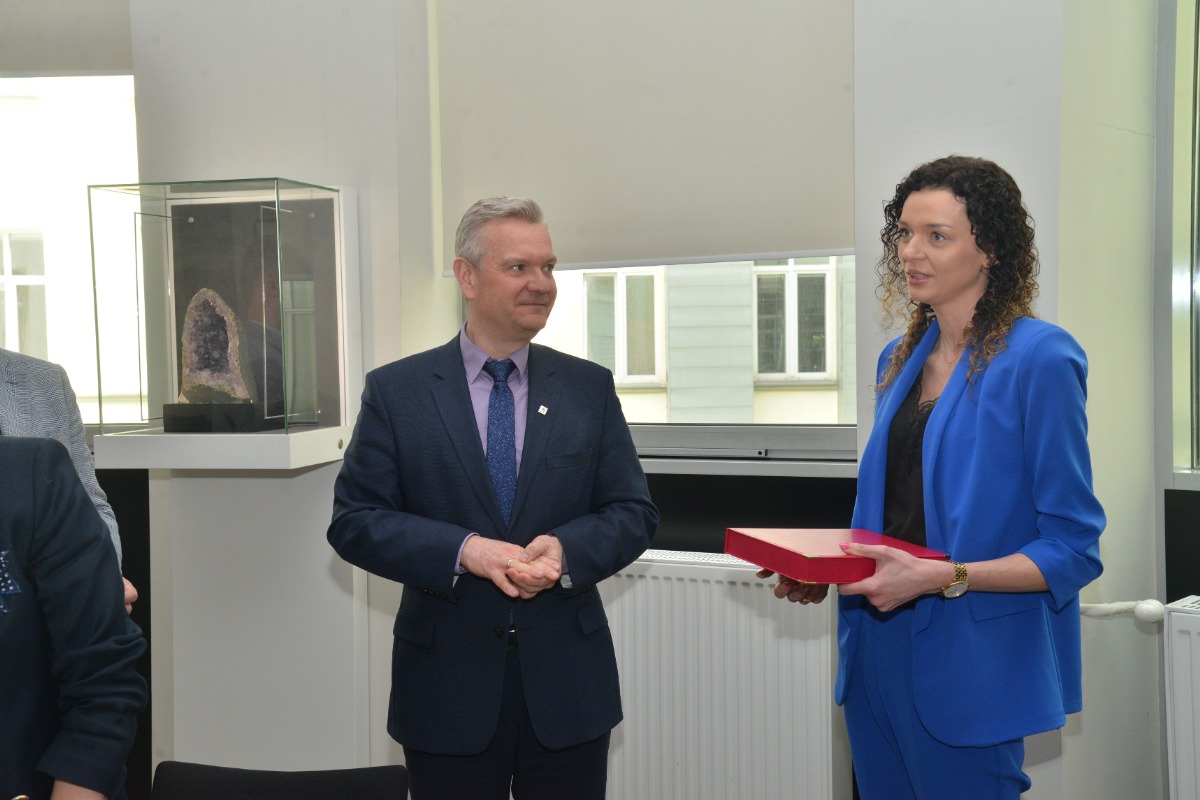 Na zdjęciu prorektor Rafał Dańko po prawej stronie Pani mgr Justyna Tyliba trzymająca w czerwone pudełko w którym znajduje się tabliczka z grawerem 