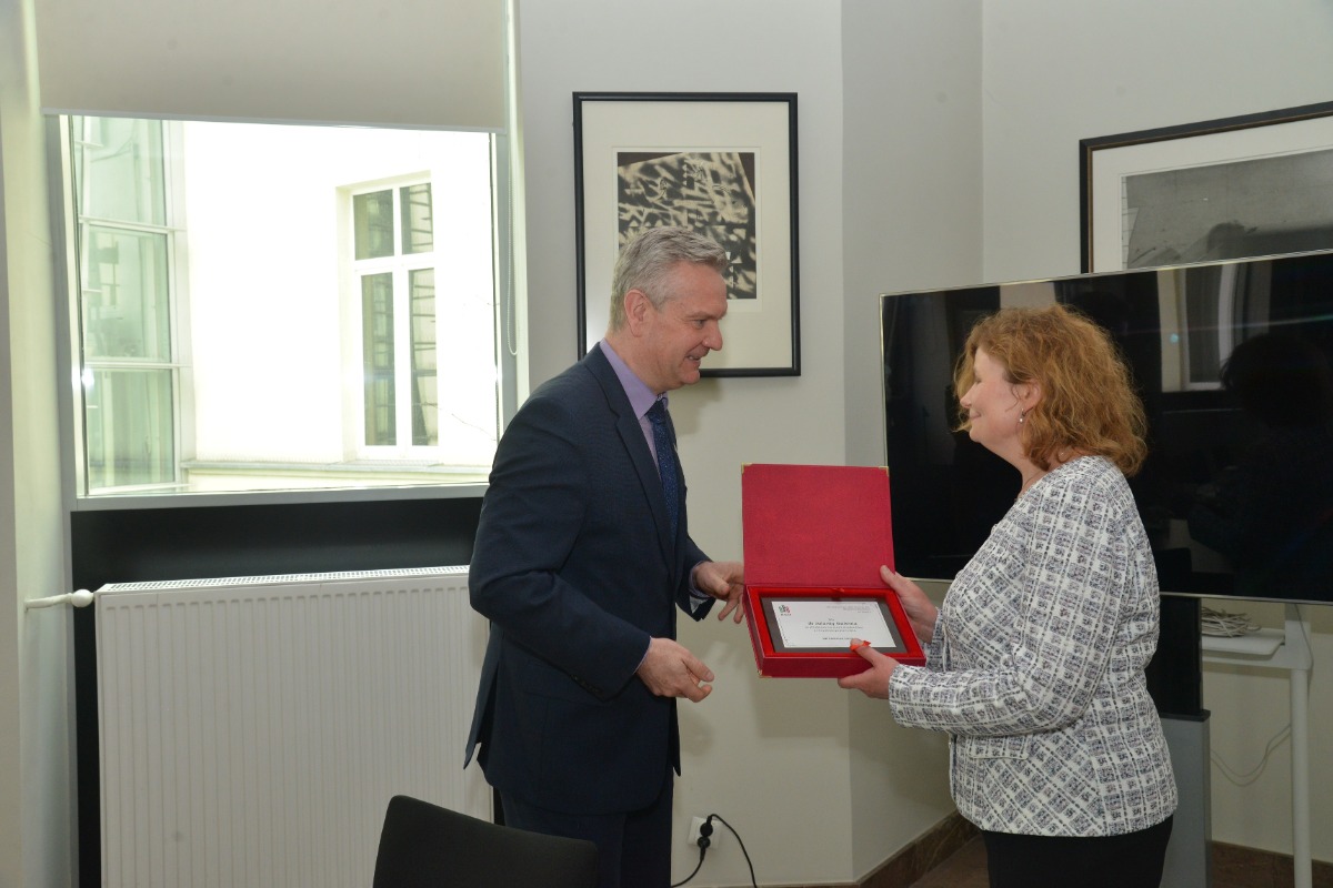Na zdjęciu prorektor prof. Rafał Dańko przekazujący tabliczkę z grawerem w czerwonym pudełku Pani dr Jolancie Goleni