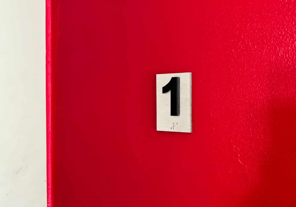 Tabliczka z numerem wypukłym oraz z informacją w alfabecie Breille’a przy drzwiach windy