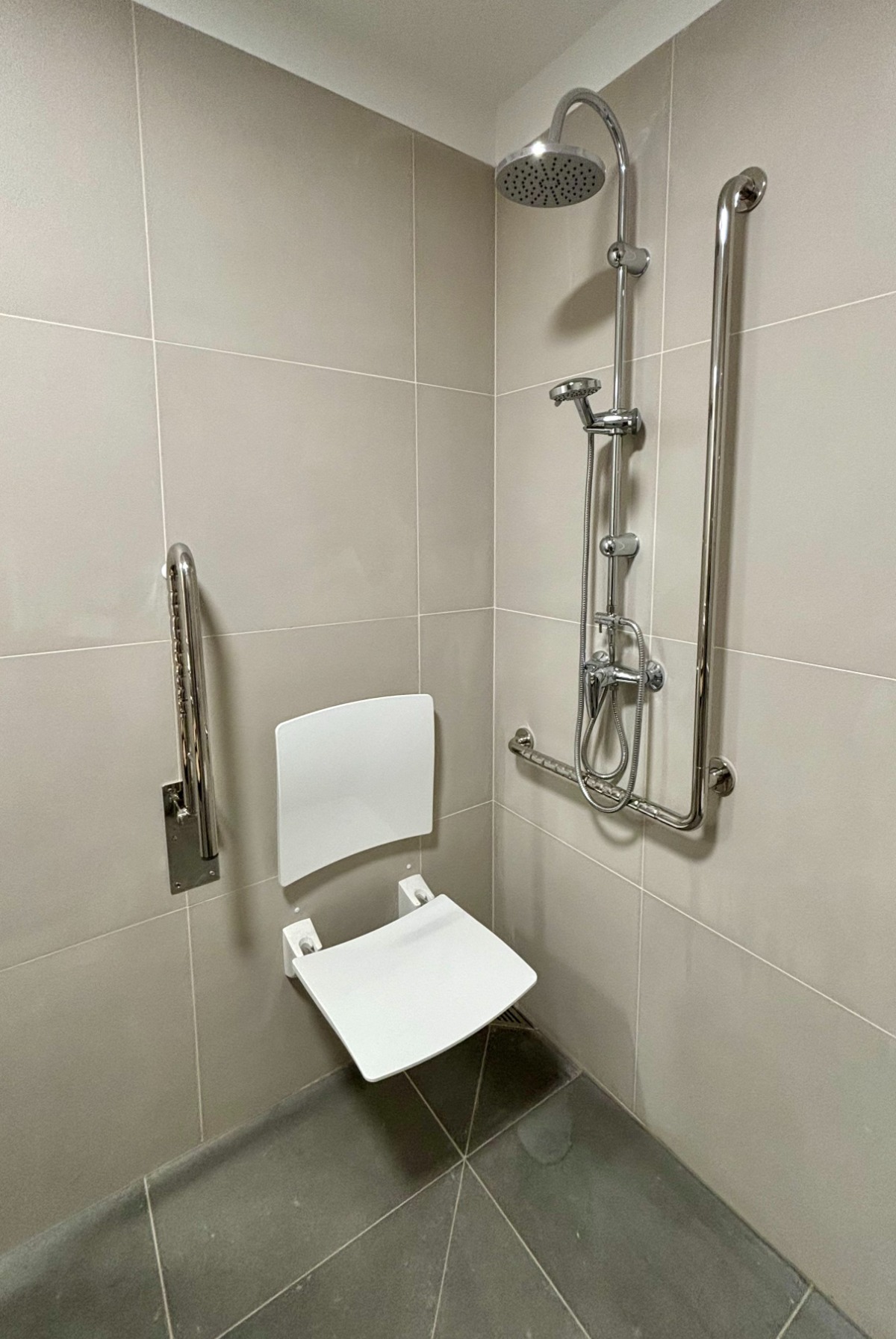 Dostosowana do potrzeb OzSzP toaleta w KS Zaścianek, widoczne składane krzesełko prysznicowe 