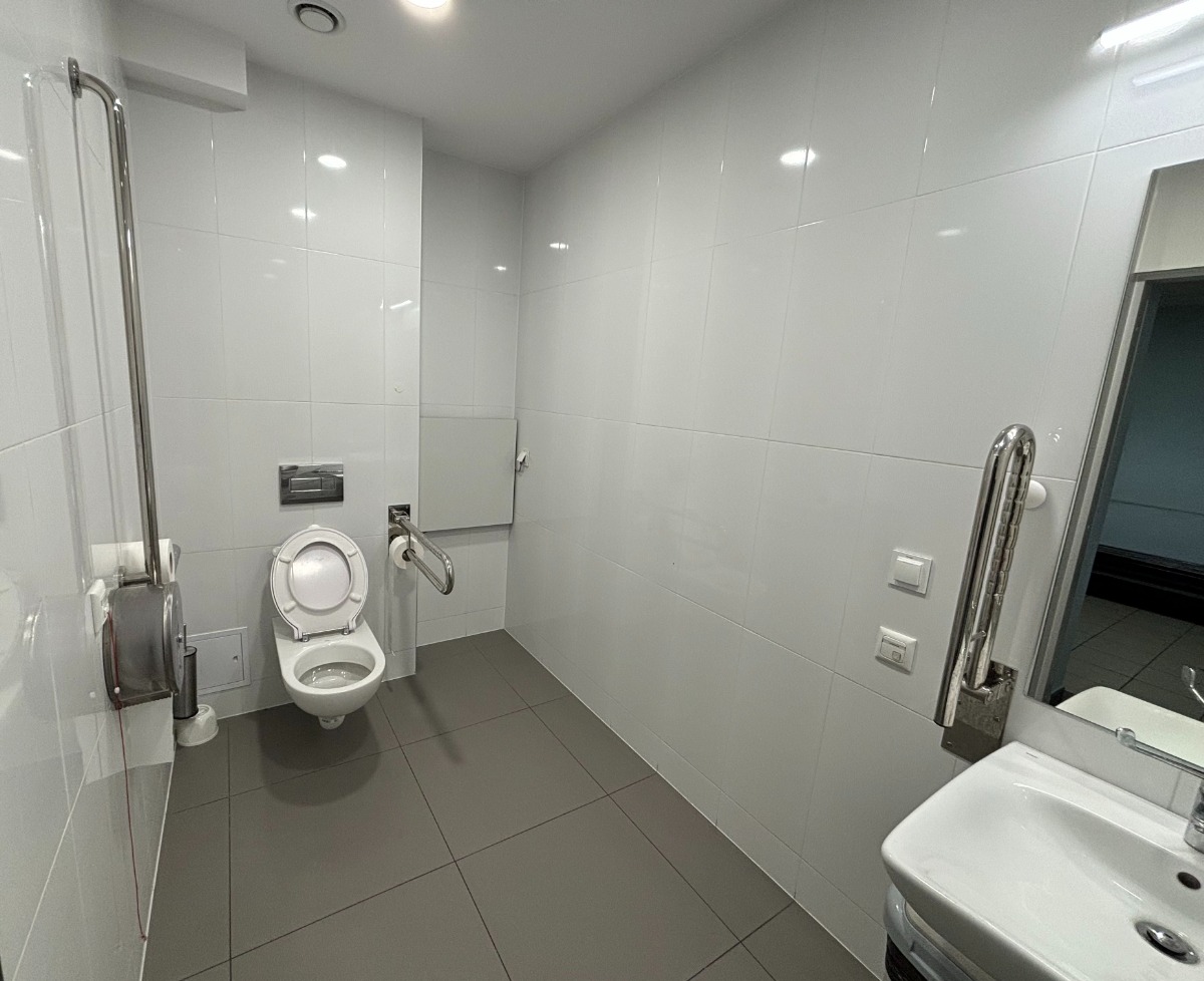 Wnętrze dostosowanej toalety z widoczną miską ustępową oraz napromiennikiem