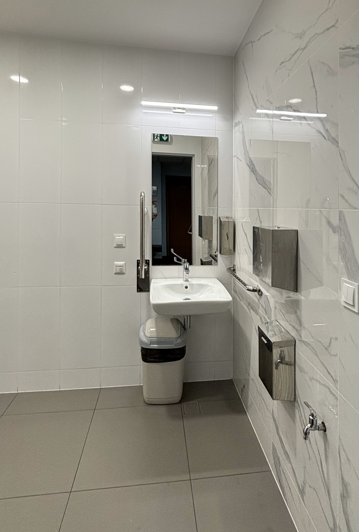 Wnętrze dostosowanej toalety z widoczną umywalką